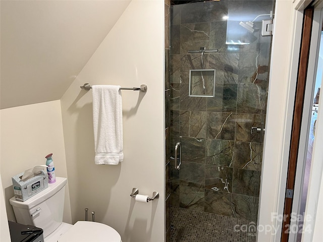 bathroom featuring a shower with door and toilet