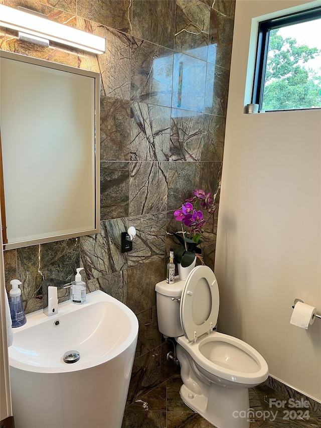 bathroom with toilet, tile walls, and sink