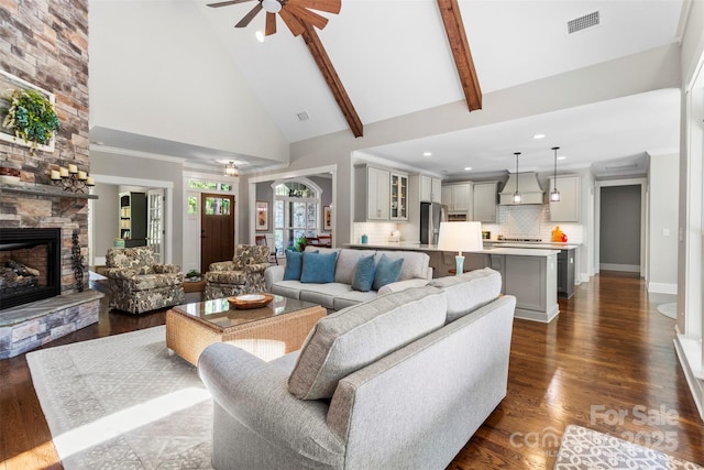 living room with high vaulted ceiling, ceiling fan, dark hardwood / wood-style floors, a fireplace, and beam ceiling