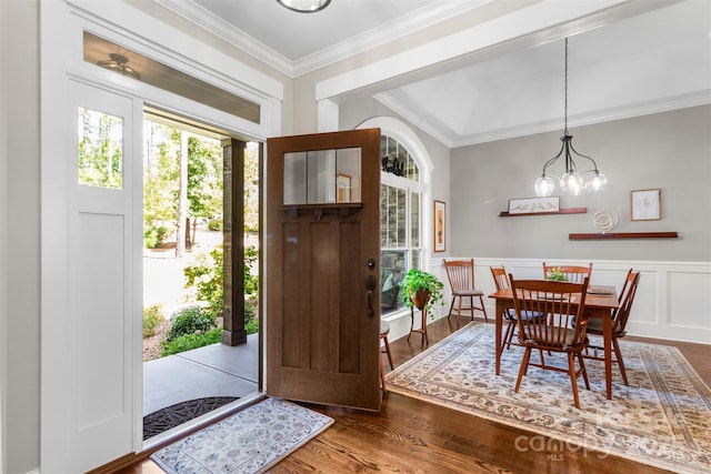 foyer entrance with crown molding, dark hardwood / wood-style flooring, and a notable chandelier