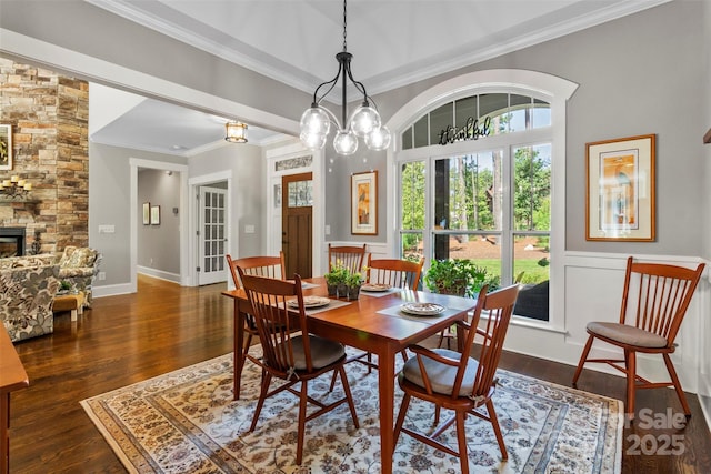 dining space with dark hardwood / wood-style floors, ornamental molding, a fireplace, and an inviting chandelier