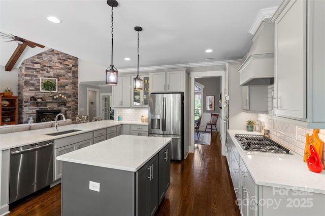 kitchen featuring decorative backsplash, gray cabinetry, stainless steel appliances, a kitchen island, and hanging light fixtures