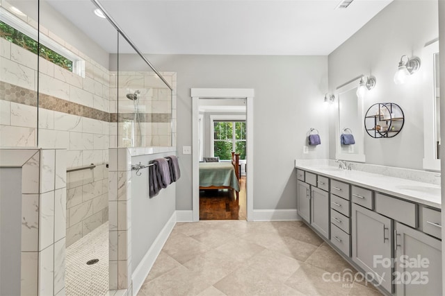 bathroom featuring tiled shower, vanity, tile patterned floors, and a healthy amount of sunlight