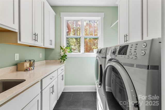 washroom with cabinets, dark tile patterned flooring, washer and clothes dryer, and sink