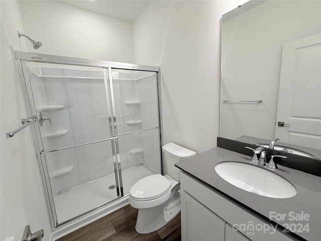 bathroom featuring hardwood / wood-style floors, vanity, toilet, and an enclosed shower