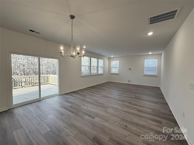 unfurnished dining area featuring a chandelier and hardwood / wood-style flooring