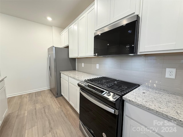 kitchen with light stone countertops, appliances with stainless steel finishes, light wood-type flooring, backsplash, and white cabinets