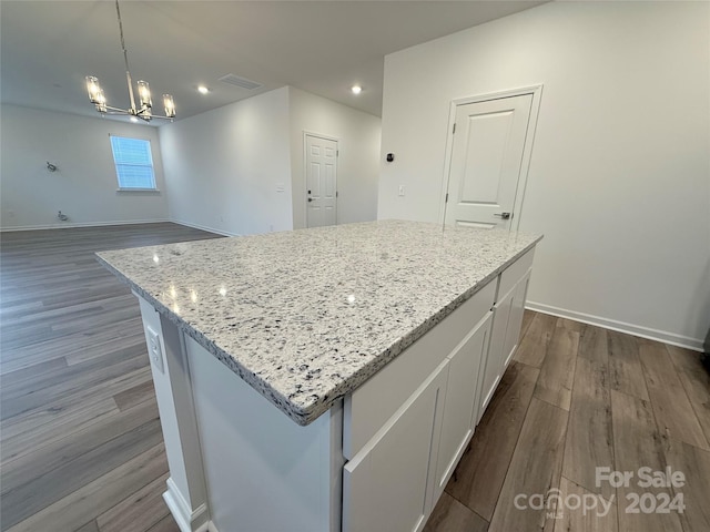 kitchen with a center island, a chandelier, decorative light fixtures, white cabinets, and hardwood / wood-style flooring