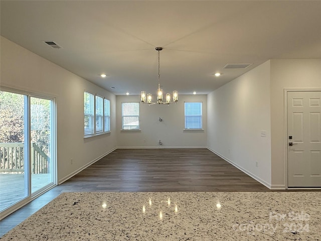 unfurnished dining area with dark hardwood / wood-style flooring and a chandelier