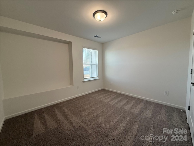 unfurnished room with dark colored carpet