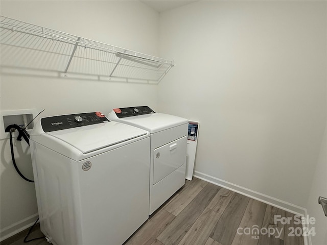 clothes washing area with hardwood / wood-style floors and washing machine and clothes dryer