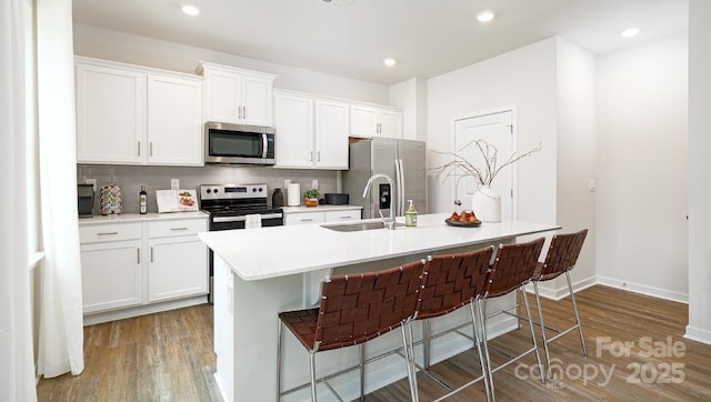 kitchen featuring a kitchen bar, sink, appliances with stainless steel finishes, and a center island with sink