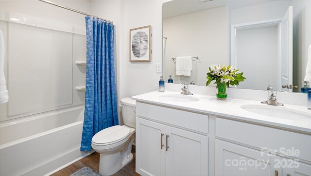 full bathroom featuring shower / bath combo with shower curtain, hardwood / wood-style flooring, toilet, and vanity