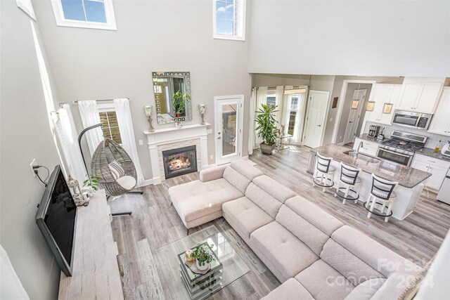 living room with a high ceiling, sink, and light wood-type flooring