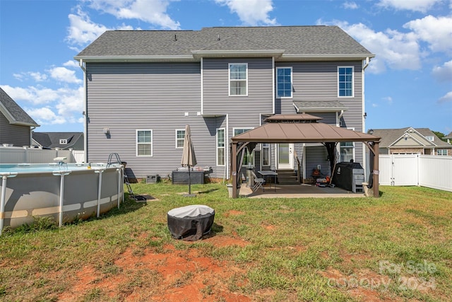 back of property with a yard, a patio, and a gazebo