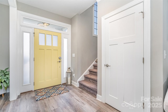 foyer entrance featuring stairway, baseboards, and wood finished floors