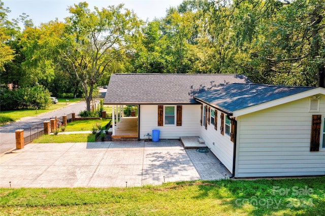 back of house featuring fence, a yard, a patio, and roof with shingles