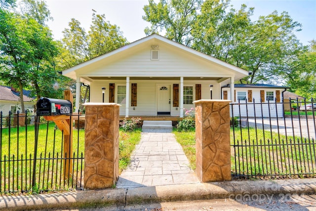 view of front of house featuring covered porch, a fenced front yard, and a front lawn
