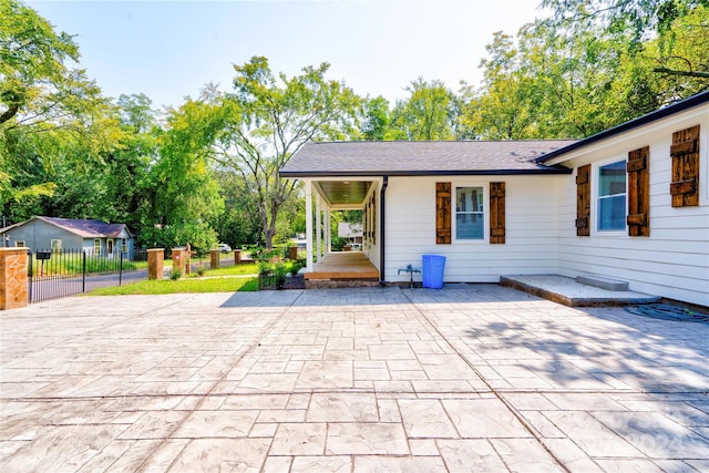 back of property featuring a shingled roof, a porch, and fence