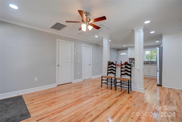 interior space with ornamental molding, sink, ceiling fan, ornate columns, and light hardwood / wood-style floors