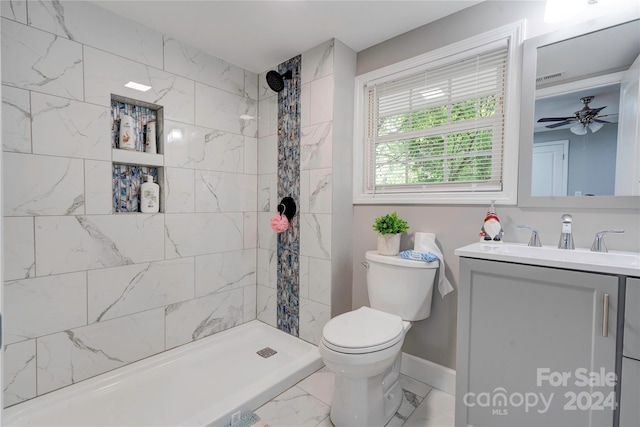 bathroom featuring tiled shower, vanity, ceiling fan, and toilet