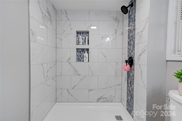 bathroom featuring toilet and a tile shower