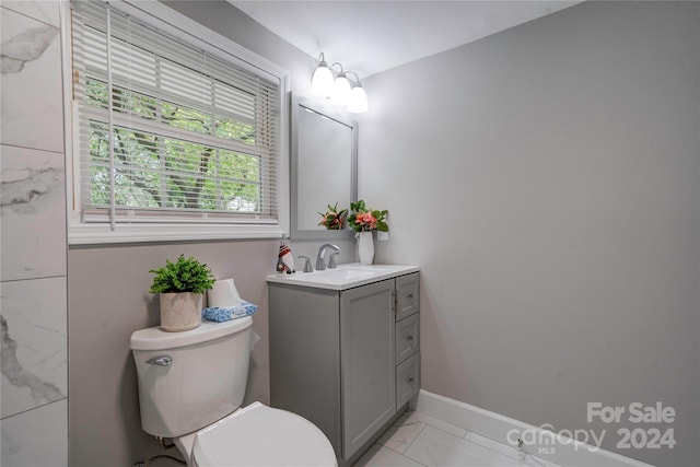 bathroom with marble finish floor, vanity, toilet, and baseboards