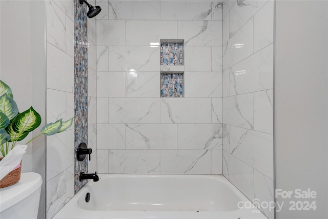 bathroom featuring toilet and tiled shower / bath