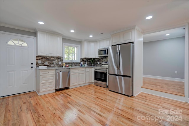 kitchen with stainless steel appliances, white cabinets, and light hardwood / wood-style floors