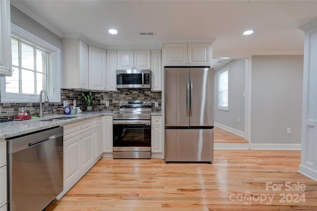 kitchen featuring light hardwood / wood-style flooring, stainless steel appliances, sink, white cabinetry, and a healthy amount of sunlight