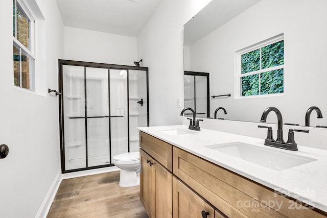 bathroom with vanity, a healthy amount of sunlight, hardwood / wood-style floors, toilet, and a shower with shower door