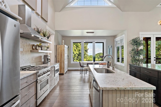 kitchen featuring light stone countertops, appliances with stainless steel finishes, sink, hardwood / wood-style flooring, and a center island with sink