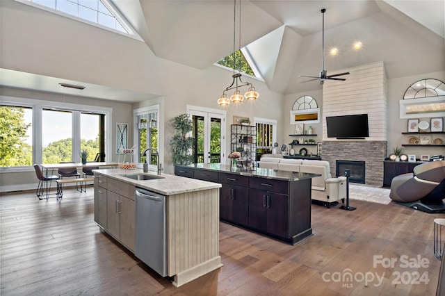 kitchen with a center island with sink, sink, dark brown cabinetry, a fireplace, and high vaulted ceiling