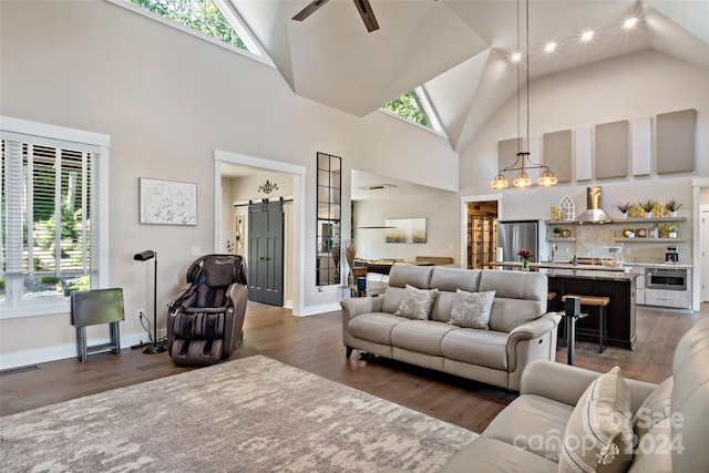 living room featuring a barn door, high vaulted ceiling, a healthy amount of sunlight, and dark hardwood / wood-style flooring