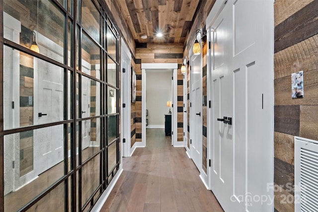 hall featuring hardwood / wood-style flooring, wooden ceiling, and wood walls