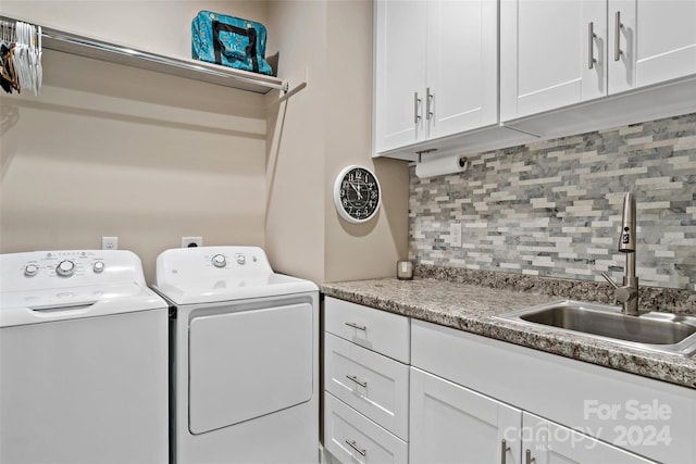 clothes washing area with cabinets, sink, and separate washer and dryer