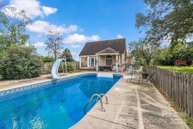 view of pool with a water slide, a patio area, and a playground