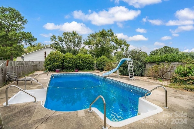 view of swimming pool featuring a water slide and a patio