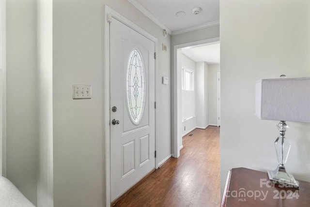 foyer entrance with dark wood-type flooring and ornamental molding