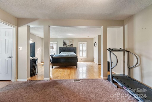 bedroom with connected bathroom, a textured ceiling, and light hardwood / wood-style flooring