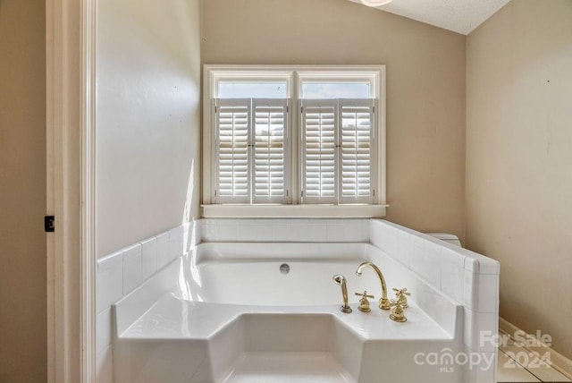 bathroom with a washtub and vaulted ceiling