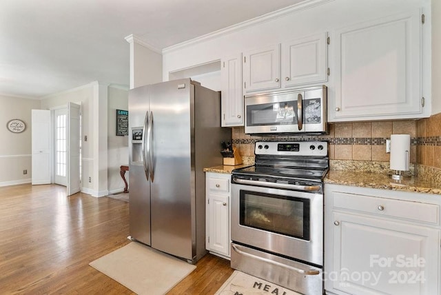 kitchen with tasteful backsplash, stainless steel appliances, white cabinets, and light hardwood / wood-style floors