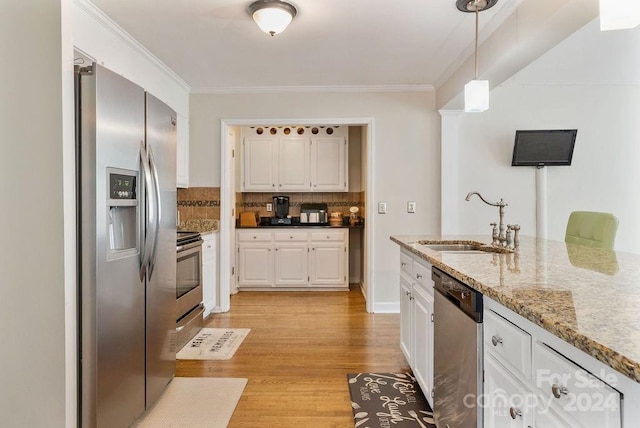 kitchen with decorative light fixtures, stainless steel appliances, sink, decorative backsplash, and light wood-type flooring