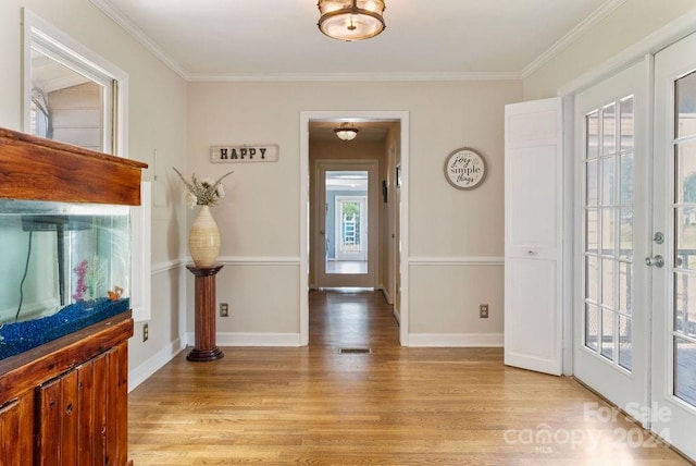 foyer featuring light hardwood / wood-style flooring, ornamental molding, and french doors