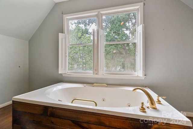 bathroom with a bathtub, wood-type flooring, and vaulted ceiling