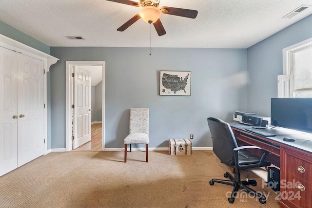 carpeted office space featuring ceiling fan and a textured ceiling