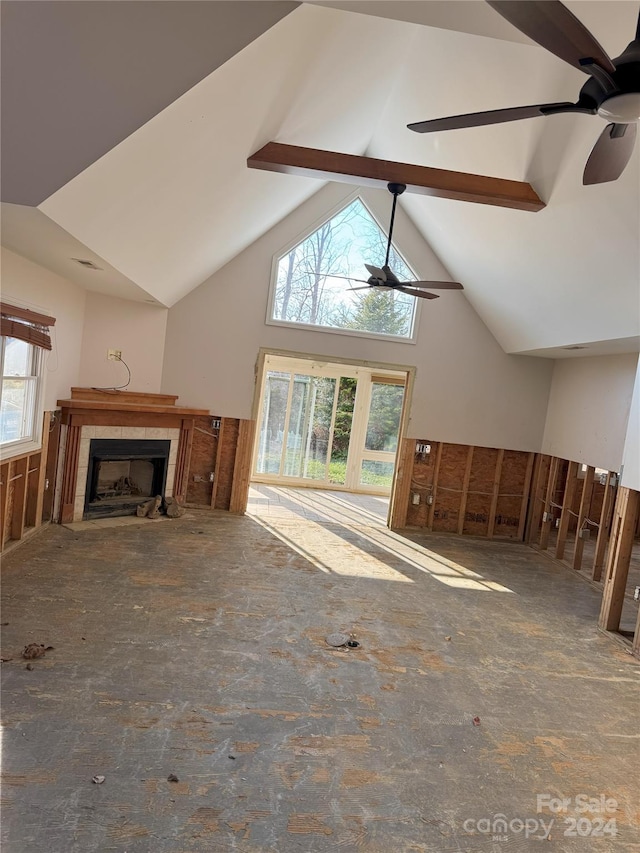 unfurnished living room with beamed ceiling, high vaulted ceiling, ceiling fan, and a tiled fireplace