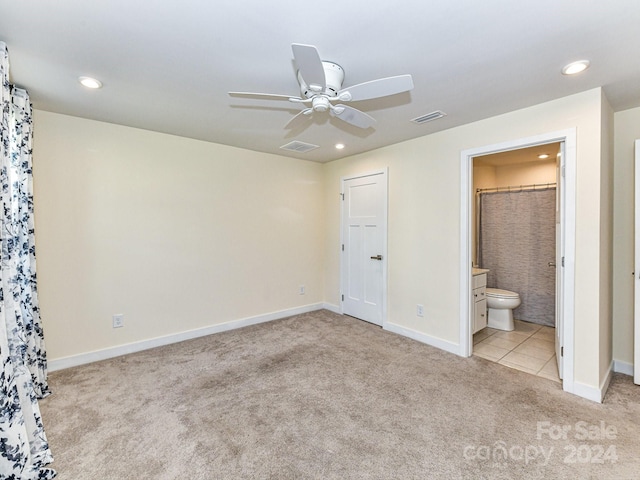 unfurnished bedroom featuring ensuite bath, light carpet, and ceiling fan