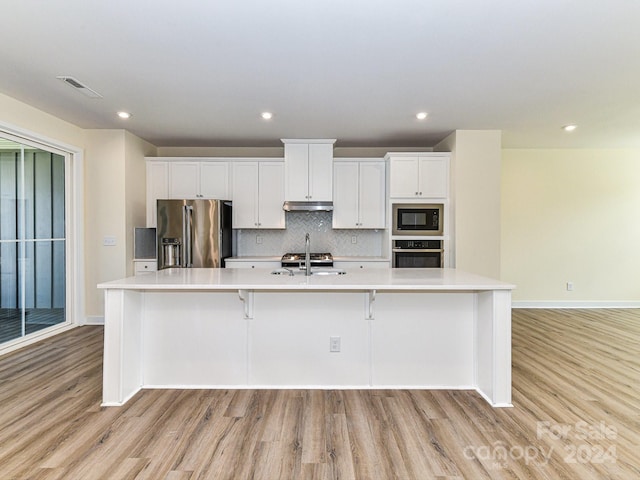 kitchen with a large island with sink, light wood-type flooring, and appliances with stainless steel finishes