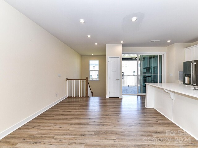 kitchen with white cabinetry, a kitchen bar, kitchen peninsula, high end refrigerator, and light hardwood / wood-style floors